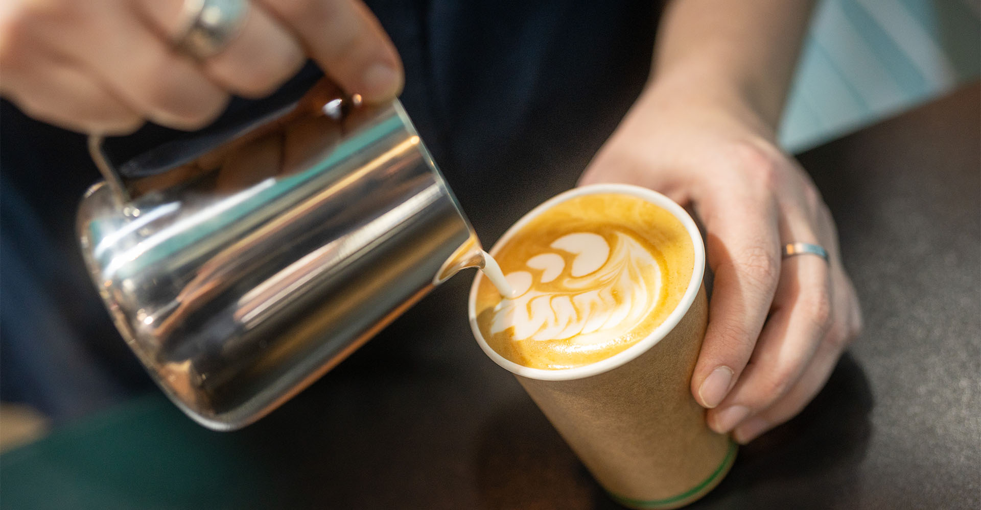 person pouring coffee into paper cup